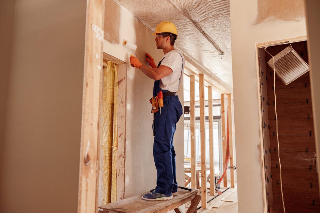 Profesional realizando trabajos de acabado y pintura en pared de obra